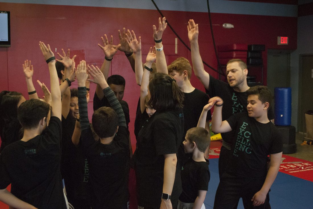 Positive camaraderie among martial arts students celebrating success with high-fives, showcasing a supportive and encouraging learning atmosphere in our training programs